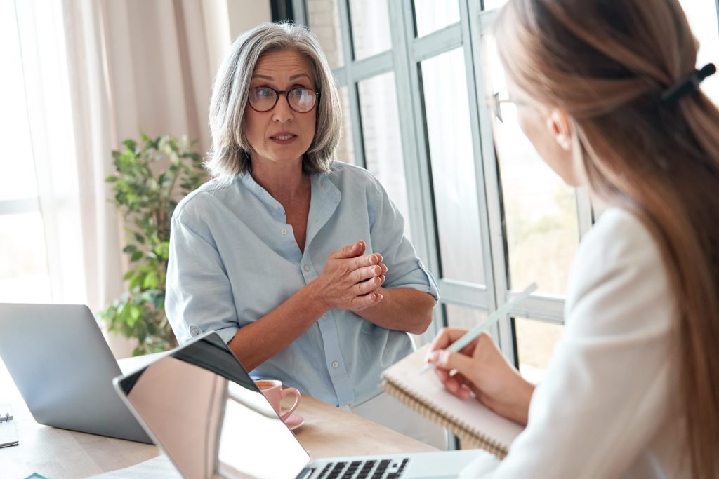 Professional in discussion with client while working on laptop