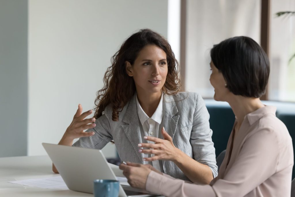 2 professional ladies in discussion while working on laptop